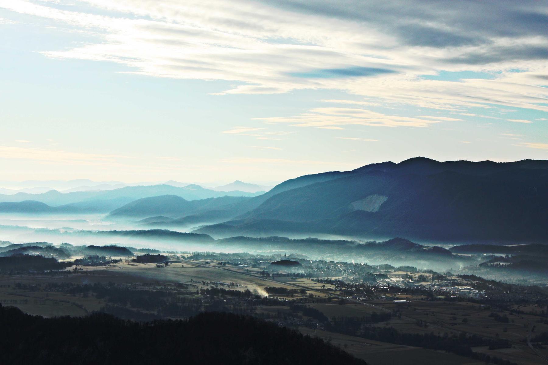 Layered blue ridgelines above a valley holding early-morning mist.